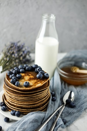 Homemade Chocolate Pancake with blueberries on a concrete gray background with milk and honey. Food photography of a healthy morning breakfast. Gauze Fabric.の写真素材