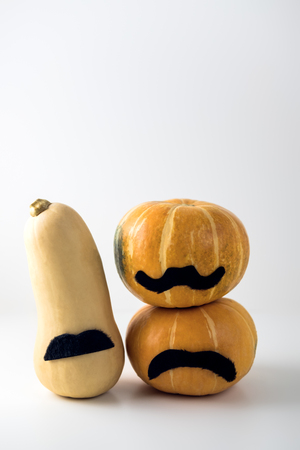 Brightly orange pumpkin with black mustache on light white background. Concept of Halloween, autumn festivals, World month of prostate cancer.の写真素材