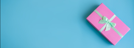 Festive holiday New Year and Christmas blue background with pink gift box. Concept of carnival,...
