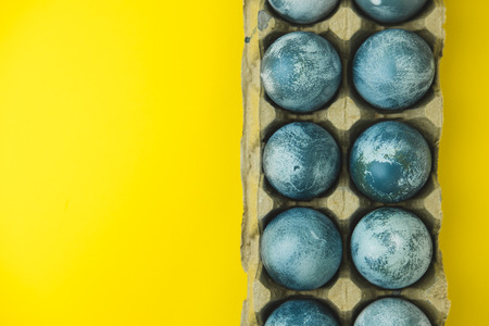 Hand painted blue Easter eggs in wreath on bright yellowの写真素材