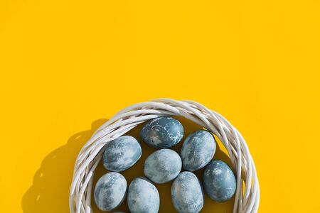 Blue textured colored Easter eggs in a nest or wreath on a bright yellow holiday background backdrop. Spring holiday concept. Copyspace. Flat lay. Top Viewの写真素材