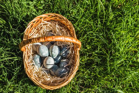 Painted blue textured easter eggs in wicker brown hand made basket. The concept of the spring holiday and egg hunting.の写真素材