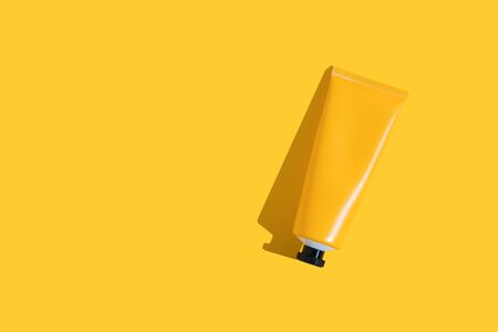 Yellow tube of sunscreen on a bright yellow background with hard shadow. Sun protection in the summerの写真素材