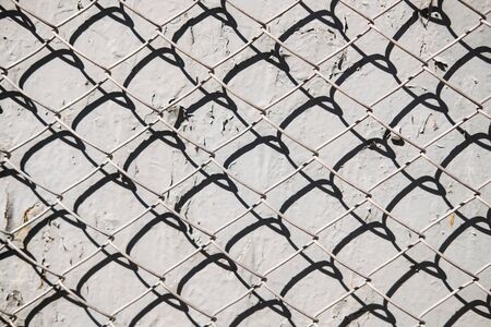 Metal mesh pattern on concrete wall background with shadow. Abstract texture