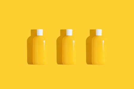 Thee yellow tube of sunscreen on a bright yellow background with hard shadow. Sun protection in the summerの写真素材