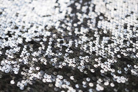 Sequin fabric texture. Shiny silver sparkling background. Clothing piece of glitter metallic for a glamorous party, celebration. Close-upの写真素材