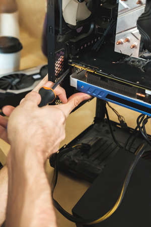 Young man repairs a computer system unit, changes parts, video card and hard drive, sets new...