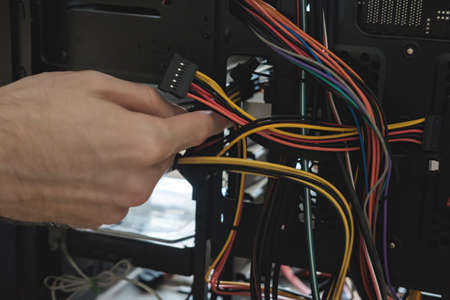 Young man repairs a computer system unit, changes parts, video card and hard drive, sets new...