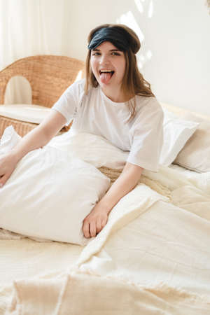 Young beautiful womanlying in comfortable bed and mask for sleep in the morning at cozy home....