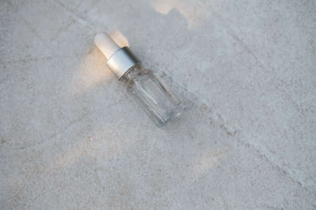 Transparent color serum bottles on gray concrete background with natural light. Trendy style....