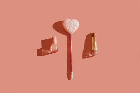 Pink lipstick, nail polish, glitter heart on pastel background with hard light shadow. Trendy style....