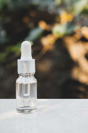 Transparent color serum bottles on gray concrete background with natural light. Trendy style. Cosmetic mockup. Copyspace.の写真素材