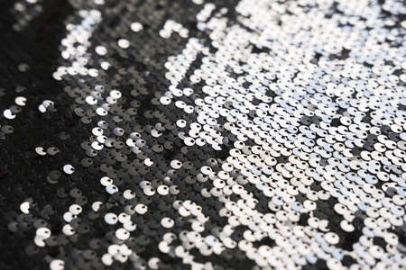 Sequin fabric texture. Shiny silver sparkling background. Clothing piece of glitter metallic for a glamorous party, celebration. Close-up.の写真素材