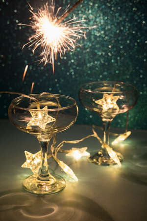 Christmas minimal festive background with star garland in glasses of champagne. Abstract Christmas and New Year color glitter blurred background shiny blue ai aqua. Bright sparkling sparklers texture.の写真素材