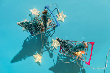 Christmas minimal festive background with star garland in supermarket basket, toy trees. Abstract Christmas and New Year color background blue ai aqua. Bright sparkling wallpaper. Flat lay. Top view.の写真素材