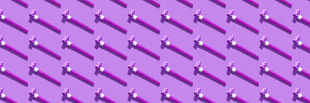 Festive air whistles on violet background. Pattern from elements of Christmas party with hard shadow. Christmas and New Year composition background for holidays. Flat lay. Top view.の写真素材