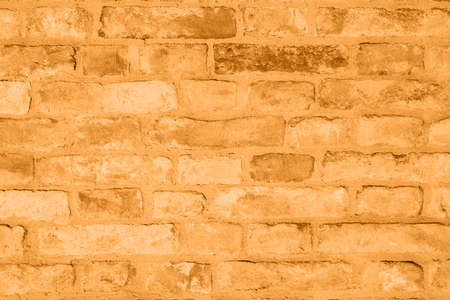 Brick orange colorful wall surface texture. Abstract grunge bright marigold color background with aging effect. Copyspace. Trendy color of the year 2021.の写真素材