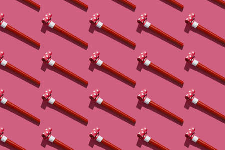 Festive air whistles on pink background. Pattern from elements of Christmas party with hard shadow. Christmas and New Year composition background for holidays. Flat lay. Top view.の写真素材