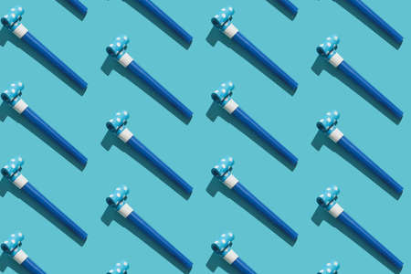 Festive air whistles on blue, pink, violet background. Pattern from elements of Christmas party with hard shadow. Christmas and New Year composition background for holidays. Flat lay. Top view.の写真素材