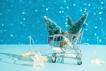 Christmas minimal festive background with star garland in supermarket basket, toy trees. Abstract Christmas and New Year color background blue ai aqua. Bright sparkling wallpaper.の写真素材