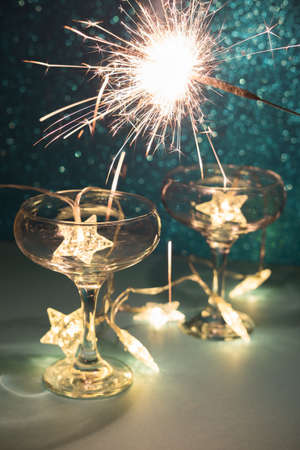 Christmas minimal festive background with star garland in glasses of champagne. Abstract Christmas and New Year color glitter blurred background shiny blue ai aqua. Bright sparkling sparklers texture.の写真素材