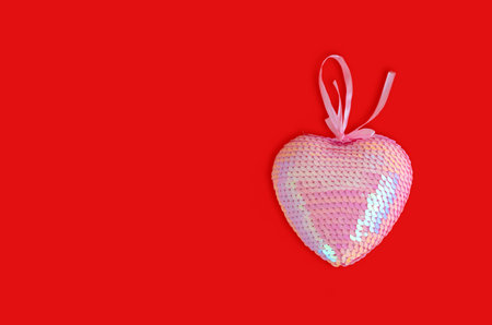 Pink wicker heart symbol made of sequins lies on the red background to Valentines Day. Top view. Flat lay. Greeting card, concept of the holiday of lovers.の写真素材