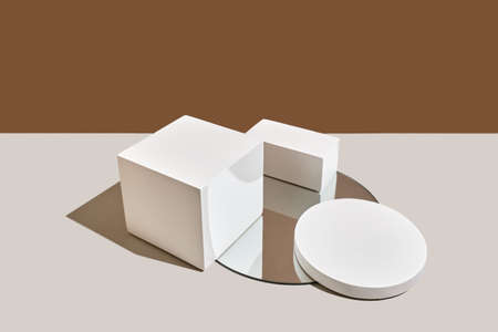 Empty white round and rectangular podium, mirror with shadows on beige natural background. Wabisabi style, earth tone. Mockup for the presentation of eco or organic products, cosmetics.の写真素材