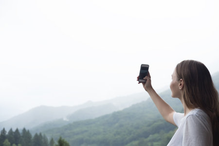 Young millennial woman admires mountains in autumn and taking selfie, picture.