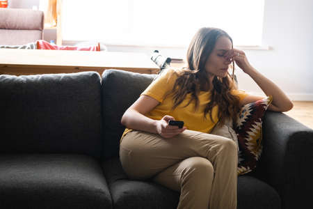 Young woman lying on the couch and using smartphone for speak with friends and relatives.