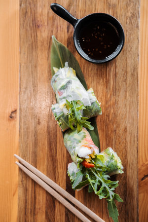 Spring rolls with shrimp, wooden chopsticks and soy sauce. Asian cuisine.