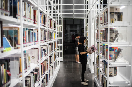 Bangkok - June 5,2017:The teenage girl is standing to read a book at white bookshelf at TCDC Libraryのeditorial素材