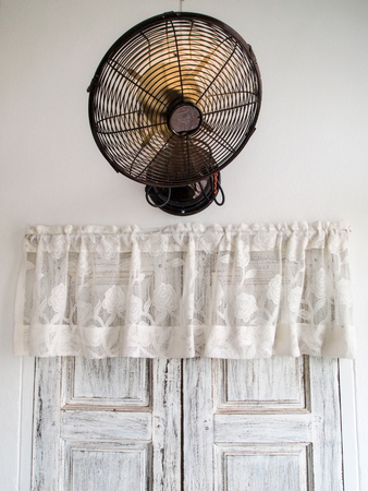 Brass vintage wall electric fan on white background , above the wooden windowの写真素材