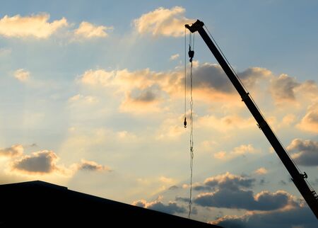 mobile crane operating, silhouettes at sunset