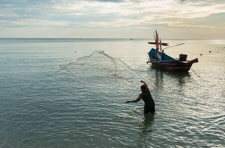 Fisherman throwing net at sunriseの写真素材