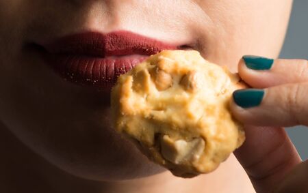 young woman eating a cookie in studio shotの写真素材