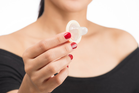 young asian woman holding condom on white background with selective focusの写真素材