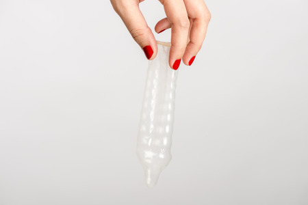 Asian woman hand holding condom on white backgroundの写真素材
