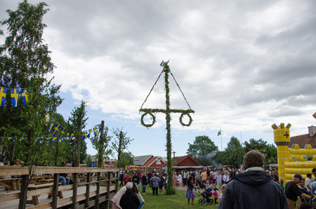Stockholm, Sweden - June 23 2017. People celebrating the swedish holiday midsummer by raising the maypole covered in flowers and leaves in Akalla, a suburb in northern Stockholm.のeditorial素材