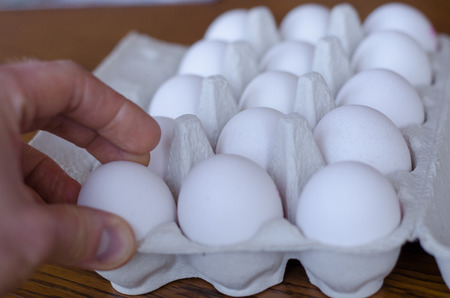 One egg among a group of eggs being picked up by a hand