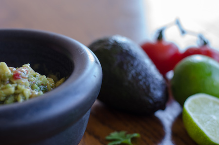 Making guacamole in a mortar with the ingredients showing on the backgroundの写真素材