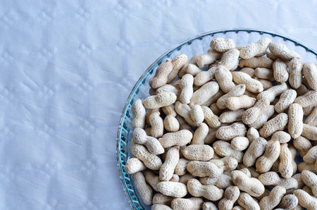 Peanuts in group on a tray of glass on table with silver clothの写真素材