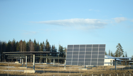 Solar panels in group on a field with a blue sky during early spring with some snow left on the...
