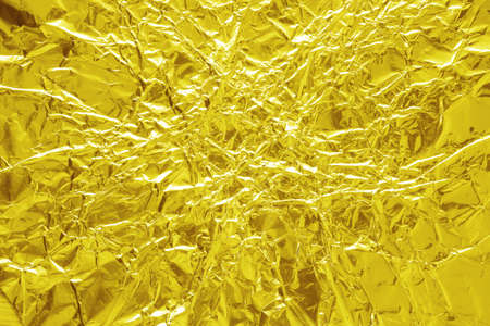 Shiny gold foil texture background, pattern of wrapping paper with crumpled and wavy.の写真素材
