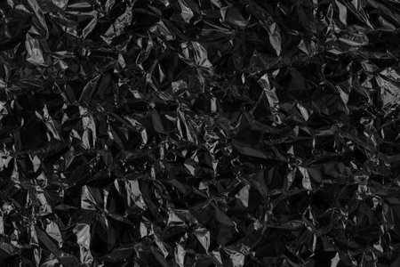 Shiny black foil texture background, pattern of wrapping paper with crumpled and wavy.の写真素材