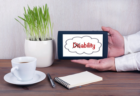 Turning the word Disability into Ability. Digital tablet computer with isolated screen in male hands.の写真素材