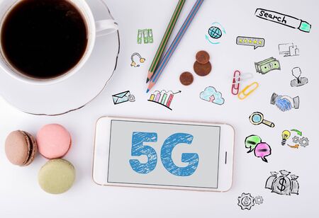 5g Business Concept. Mobile phone and coffee cup on a white office desk.の写真素材