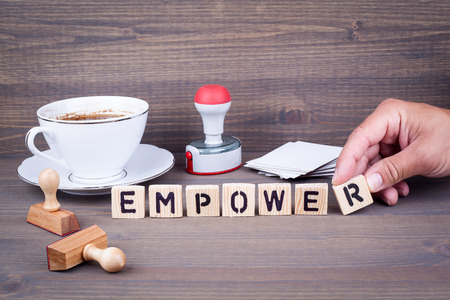 empower. Wooden letters on dark background. Office deskの写真素材