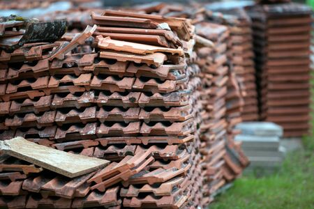 old clay tile roof tiles stacked on wooden pallets. The background for construction restoration and logistics.の写真素材