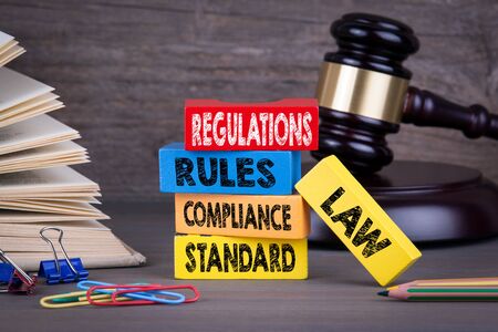 regulations concept. Wooden gavel and books in background.