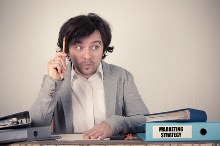 Marketing Strategy text on the binder, worried bussinesman thinking by the work desk.の写真素材